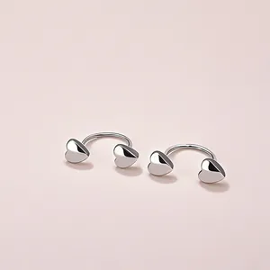 Minimalist silver U-shaped heart earrings featuring polished 3D heart studs on pink background
