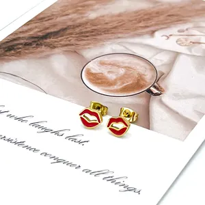 Detalle de pendientes de labios en esmalte rojo y oro sobre tarjeta decorativa