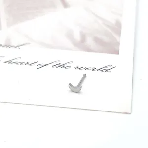 Detailed view of a silver crescent moon nose stud resting on a decorative postcard