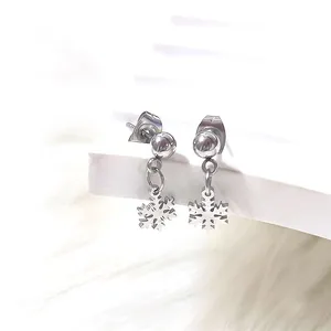 Detail shot of silver snowflake earrings with ball studs on white plush background