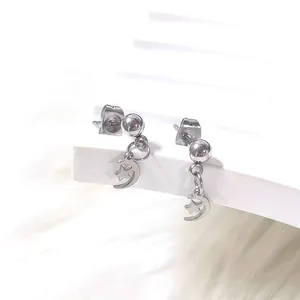 Close-up of star and moon dangle earrings on a plush white background with metallic sheen