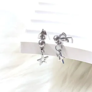 Close-up of polished titanium steel stud earrings with hollow star charms on white stand