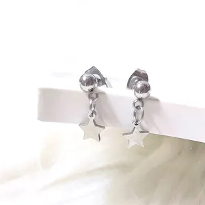 Close-up of titanium steel ball earrings with hollow star pendants on white display