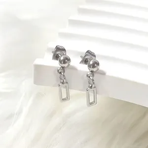 Macro shot of silver titanium steel ball stud earrings with minimalist hollow rectangle drop