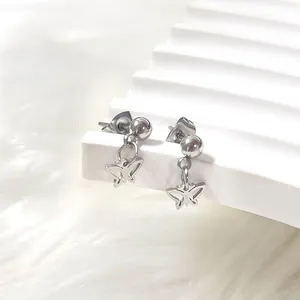 Close-up of silver steel butterfly dangle earrings on a soft white decorative stand