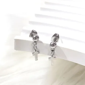 Macro detail of silver titanium steel cross pendant earrings on a white display