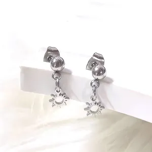Detailed macro view of silver titanium steel ball stud earrings with hollow sun pendant
