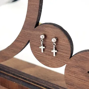 Macro view of polished stainless steel ball studs and hanging minimalist cross charms
