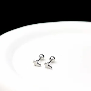 Primer plano detallado de pendientes de cruz plateados sobre un plato de cerámica blanca