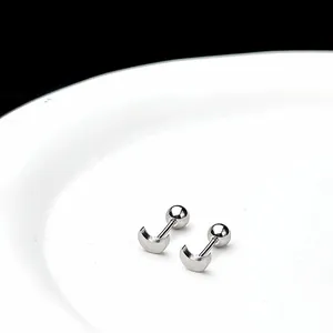 Vista macro de pendientes de media luna de plata con acabado de metal pulido en bandeja