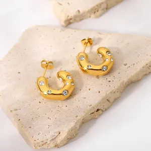 18K gold plated stainless steel C-shape earrings with zircon stones on stone background