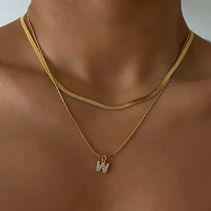 Close-up of a double-layered gold snake chain with a diamond-encrusted letter W pendant
