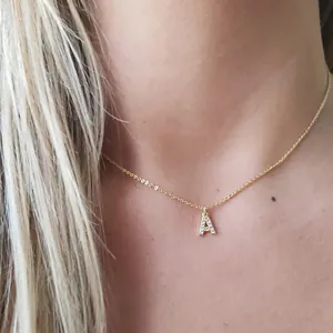 Detail shot of a crystal-encrusted letter A pendant on a gold snake chain necklace