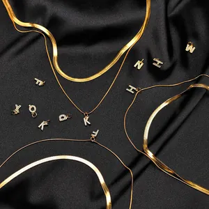 Macro shot of gold plated herringbone chain with micro-paved rhinestone letter pendants