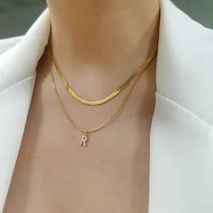 Gold layered necklace with herringbone chain and sparkling crystal letter R pendant