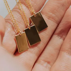 Detailed close-up of three polished gold square pendant necklaces on a hand