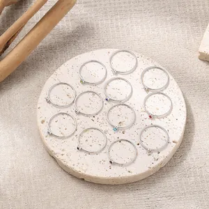 Macro detail of twelve silver stackable rings with colorful birthstones on stone tray