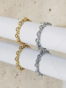 Vue détaillée de bagues à maillons d'or et d'argent reflétant sur une surface en pierre