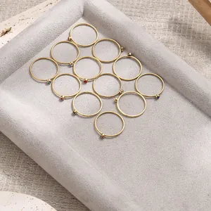 Set of 12 minimalist gold birthstone rings with colorful cubic zirconia in a jewelry tray