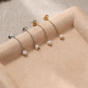 Elegant freshwater pearl drop earrings in gold and silver finish on a velvet tray