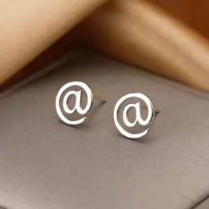 Vue macro d'un clou d'oreille en acier inoxydable argenté avec un design poli de symbole at