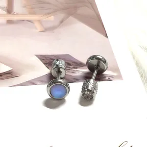 Detalle macro del piercing de acero inoxidable con piedra azul y cierre de rosca barra