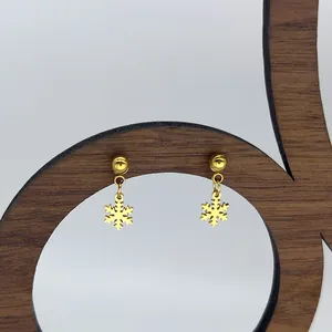 Λεπτομέρεια από χρυσά σκουλαρίκια χιονονιφάδα σε ξύλινη βάση παρουσίασης