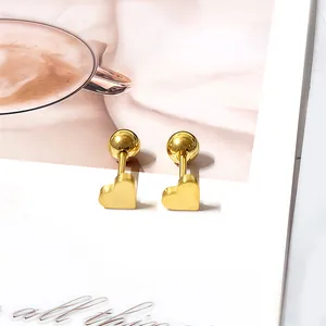Boucles d'oreilles cœur en or minimalistes avec fermoir à vis sur fond de magazine