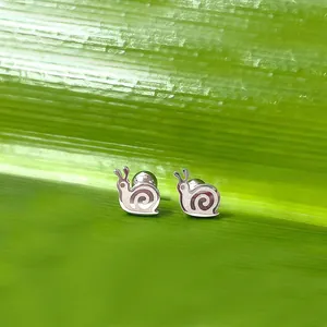 Vue macro de boucles d'oreilles escargot en métal poli sur un fond de feuille verte