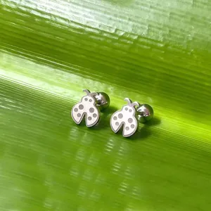 Boucles d'oreilles coccinelle en acier titane argenté sur fond de feuille verte
