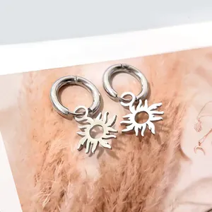 Detalle de pendientes de aro con colgante de sol sobre fondo de moda decorado