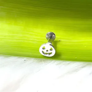 Dettaglio ravvicinato di un piercing in acciaio al titanio a forma di zucca su verde