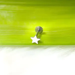 Vista macro di un piercing labiale in titanio argentato a forma di stella su pelliccia finta