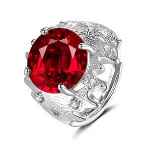 Détail d'une bague avec pierre précieuse rouge ovale, accents diamant et anneau argent