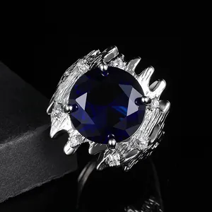 Gros plan d'une bague argentée texture lave avec une grande pierre centrale bleu foncé