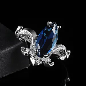 Luxury silver fleur-de-lis crown ring with large marquise-cut sapphire and micro-pave diamonds