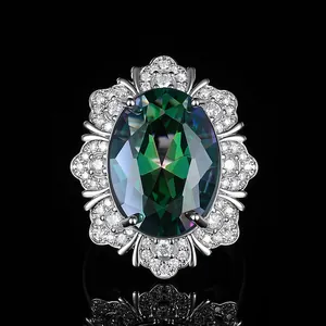 Luxuriöser Ring mit ovalem grünem Edelstein und Diamant-Halo auf schwarzem Spiegelgrund