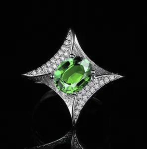 Macro detail of oval green gemstone ring with star-shaped pave diamond setting