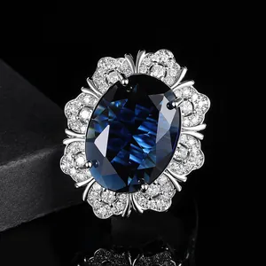 Luxuriöser Ring mit ovalem tiefblauem Saphir und floralem Diamant-Halo auf Schmuckkästchen