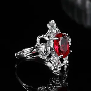 Silver marine ring featuring large oval ruby-red gemstone with seashell and coral carvings