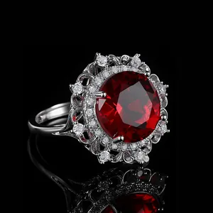 Luxury cocktail ring featuring a large red gemstone and white zircons on black background