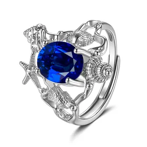 Macro detail of silver ocean-themed ring with starfishes and blue oval gemstone