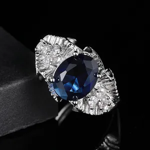 Bague luxueuse avec pierre précieuse bleue ovale et texture argentée avec accents