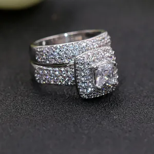 Detailopname van de zilveren ringenset met prinsesgeslepen steen en dubbele halo