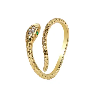 Detail of gold snake ring featuring green gemstone eyes and textured diamond scales