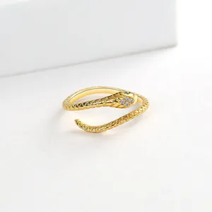 Detailed view of gold plated snake ring featuring sparkling white stones and green eyes