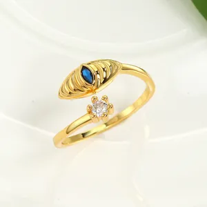 Macro view of gold open ring featuring blue evil eye gemstone and small flower detail