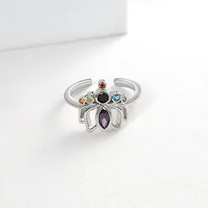Macro detail of silver lotus ring with multi-color zircons on white background