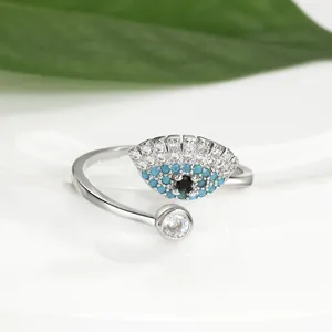 Détail de la bague ajustable œil bleu avec cristaux et feuille verte sur fond blanc épuré