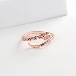Close-up of rose gold snake ring with green gem eyes and white zircon scale details